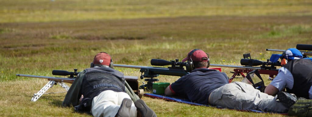 A group of target shooters prone aiming down the scopes of their rifles