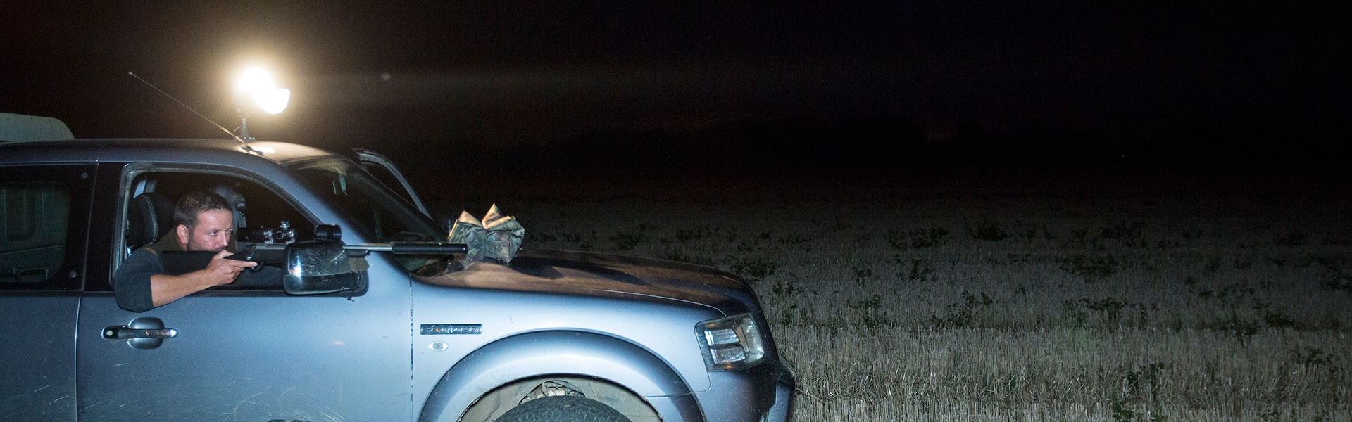 A night shooter in their vehicle aiming down the sights of their rifle