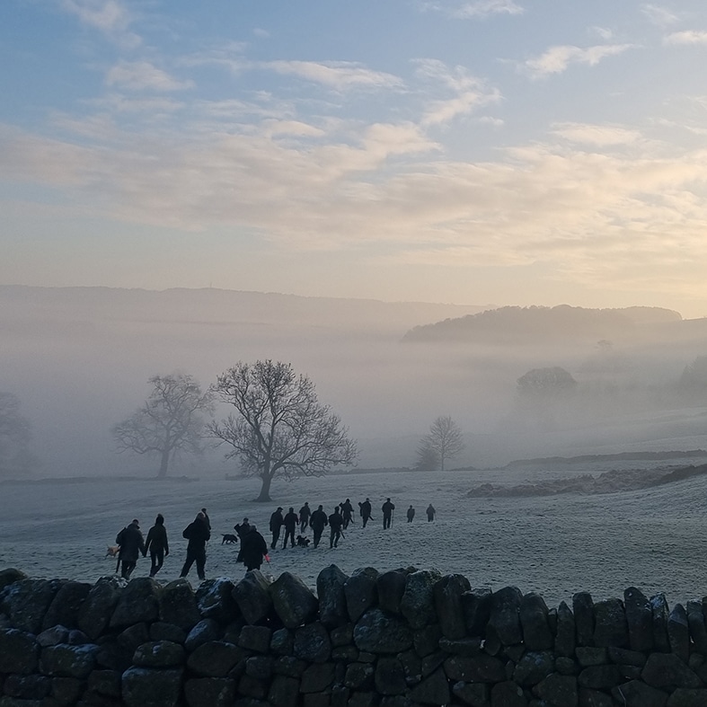 A group of shooters walking through a field in the winter