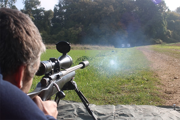 A target shooter aiming down a scope at a target