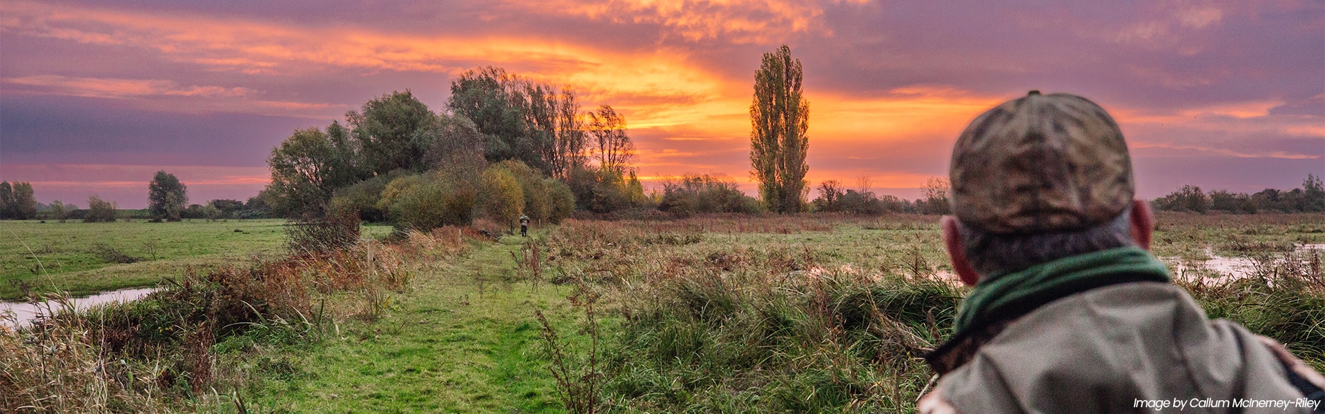 A wildfowler looking across a field at dawn