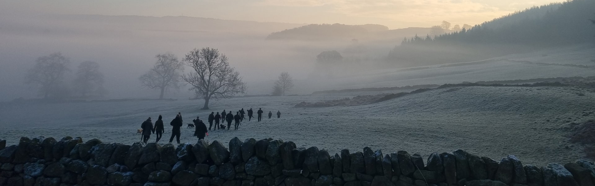Game shooters walking through a frosty field